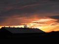 Dairy barn cupolas silhouetted by vibrant orange setting sun Royalty Free Stock Photo