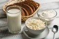 Dairy farm food: curd cheese and cream in bowls, milk and fresh bread in basket on wooden background Royalty Free Stock Photo