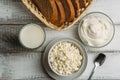 Dairy farm food: curd cheese and cream in bowls, milk and fresh bread on white wooden background, top view Royalty Free Stock Photo