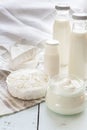 Dairy products. Milk in glass bottle, yogurt, sour milk cheese, sour cream in glass jar, camembert, brie on light wooden table