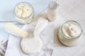 Dairy products. Milk in glass bottle, yogurt, sour milk cheese, sour cream in glass jar, camembert, brie on light wooden table