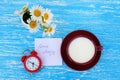 Daisy flowers, alarm clock and cup of milk Royalty Free Stock Photo