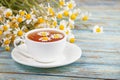 Daisy flowers in a white cup of tea, chamomile herbs on wooden background. Herbal medicine Royalty Free Stock Photo