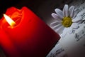Daisy and Red Candle on Music Notes Sheet Royalty Free Stock Photo