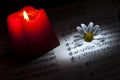 Daisy and Red Candle on Music Notes Sheet Royalty Free Stock Photo