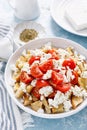 Dakos or koukouvagia salad. Classic recipe Cretan barley rusk salad with fresh tomato, mizithra cheese and oregano