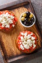 Dakos or Ntakos traditional Greek starter made of dried bread with tomato feta, oregano and olive oil closeup on the wooden board