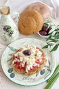 Dakos traditional Greek appetizer on a traditional plate with ceramic olive oil jar, dry rye bread, olives and olive branch.