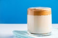 Dalgona coffee on a blue background. Fashion trend drink of milk and sweet whipped foam