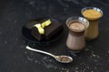 Dalgona coffee and cocoa in glass transparent glasses. Nearby lies a metal spoon with instant coffee, and a chocolate dessert on a