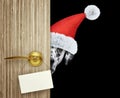 Dalmatian dog in red christmas santa claus hat looking out the door entrance at home with empty card. Isolated on black Royalty Free Stock Photo