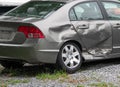 Damage to the rear panel, door and tire of a gray car due to an automobile accident.