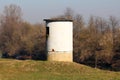 Damaged abandoned old Second world war concrete and bricks bunker on elevated foundation next to calm river Royalty Free Stock Photo