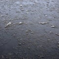 Damaged asphalt road with potholes, filled with water with ice, Royalty Free Stock Photo