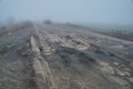 Damaged asphalt road with potholes in fog