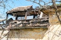 Damaged and broken collapsed roof of the abandoned house after fire from grenade bomb, with tiles and blue sky background Royalty Free Stock Photo