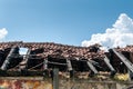 Damaged and broken collapsed roof of the abandoned house after fire from grenade bomb with tiles and blue sky background Royalty Free Stock Photo