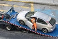 Damaged car being loaded onto tow truck by a worker Royalty Free Stock Photo