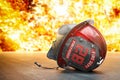 Damaged firefighter helmet on a floor with fire flames on background. Dangerous and hard work of a firefighter concept