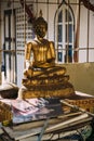 Damaged golden buddha statue sitting behind pile of papers and books