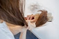 Damaged Hair, frustrated asian young woman, girl hand in holding brush splitting ends messy while combing hair, unbrushed dry long Royalty Free Stock Photo