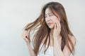 Damaged Hair, frustrated asian young woman, girl hand in holding splitting ends, messy unbrushed dry hair with face shock, long Royalty Free Stock Photo