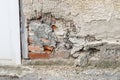 A damaged house wall and flaked exterior plaster with a large hole, Germany
