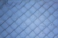 Damaged metal net on a blue white gray shabby dirty wall cracked. rough surface texture