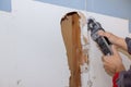 Damaged plasterboard with repair home of man cutting gypsum drywall on using angle hand electric power tools