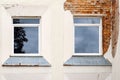 Damaged plastered brick wall with two windows