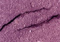 Damaged purple toned asphalt surface.