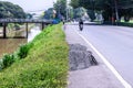 Damaged road with potholes near canal in counreyside