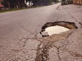Damaged road surface with deep pothole. Royalty Free Stock Photo