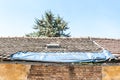 Damaged roof with tiles on the old house covered with plastic nylon to protect interior from rain water