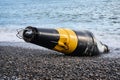 Damaged sea buoy - cardinal danger mark - washed ashore after a storm Royalty Free Stock Photo