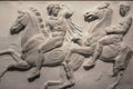A damaged section of the Elgin Marbles relief originally on the Parthenon in Greece showing two men on horses in a battle