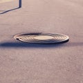 Damaged sewer manhole on the asphalt path, broken metal cover close-up Royalty Free Stock Photo