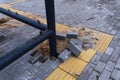 Damaged sidewalk tiles and broken bricks near a metal railing in an urban setting Royalty Free Stock Photo
