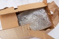 Damaged and torn open cardboard box for transporting things. Top view. Close-up. Bubble wrap keeps things and utensils Royalty Free Stock Photo