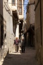 Two elderly Arabic men one wearing religious hat are walking in a narrow alley Royalty Free Stock Photo