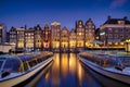 Damrak, Amsterdam, Netherlands. View of houses and boats during sunset. The famous Dutch canals and boats. A cityscape in the even Royalty Free Stock Photo