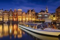 Damrak, Amsterdam, Netherlands. View of houses and boats during sunset. The famous Dutch canals and boats. A cityscape in the even Royalty Free Stock Photo