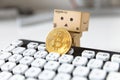 Danbo holding bitcoin next to computer keyboard