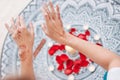 Dance of female hands with mehendi over the altar of candles and rose petals, women practices