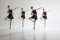 Dance in harmony. Beautiful teen girls, ballerinas in black leotards and pointe in motion, dancing against gray studio