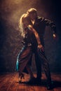 Dance and love concept. Young couple in elegant evening dresses posing in the room filled with dramatic light. Two Royalty Free Stock Photo