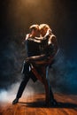 Dance and love concept. Young couple in elegant evening dresses posing in the room filled with dramatic light. Two Royalty Free Stock Photo