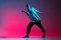 Full-length horizontal portrait of young male hip-hop dancer practising isolated over gradient pink purple background in Royalty Free Stock Photo