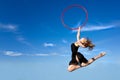 Jymnast with hoop jumping against blue sky Royalty Free Stock Photo