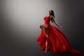 Dancer in Red Dress Jumping. Woman Ballerina Expressive Balance Dance Flying Fabric in Air. Fashion Model Dancing over Gray Studio Royalty Free Stock Photo